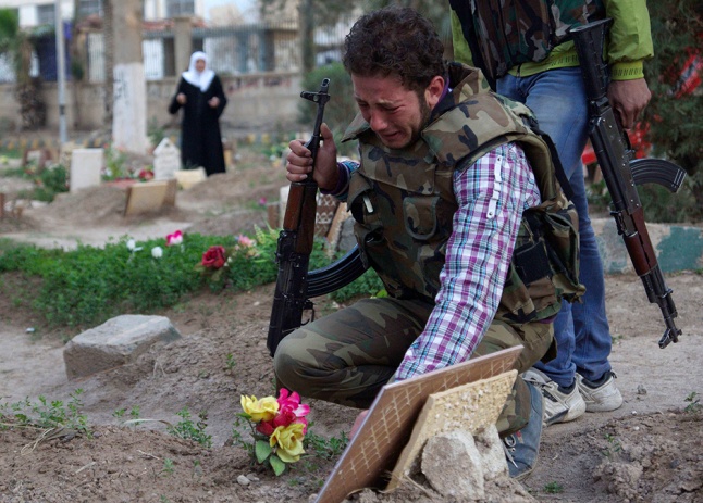 A Free Syrian Army fighter mourns at the grave of his father in a public park that has been converted into a makeshift graveyard in Deir el-Zor